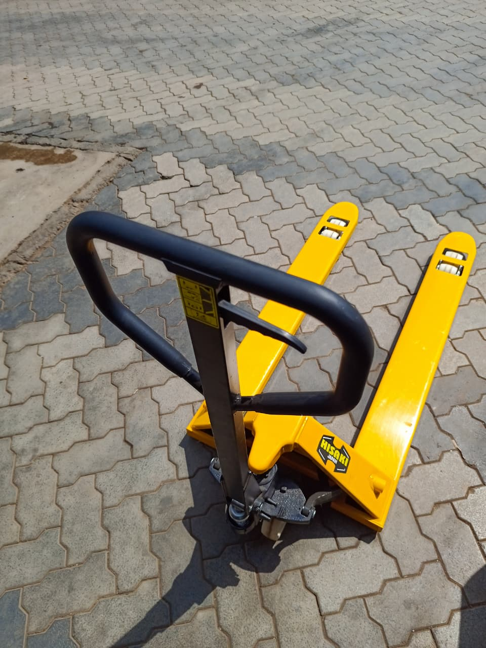 Hisaki 3-ton wide pallet truck handle and fork detail view on paving stones